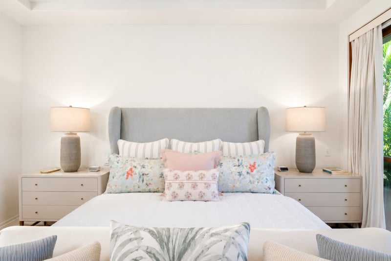 Primary bedroom detail at The Resort at Kapalua Bay MON-2206 — layered striped and floral pillows on the king bed's wingback headboard MON-2206