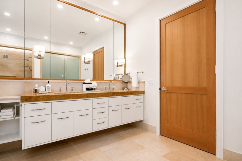 Primary bath vanity at The Resort at Kapalua Bay MON-2206 — dual sinks and mirrored medicine cabinets with warm sconce lighting MON-2206