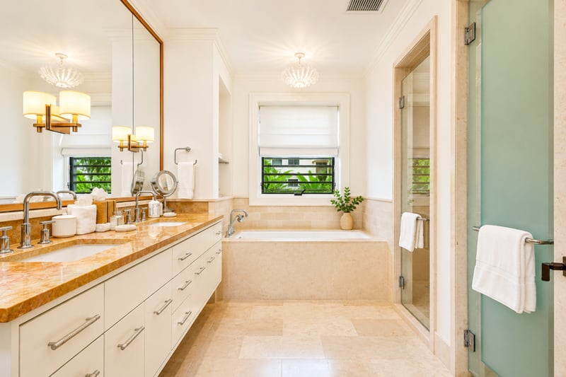 Guest bathroom at The Resort at Kapalua Bay MON-2206 — glass-enclosed shower and vanity beneath a crystal pendant light