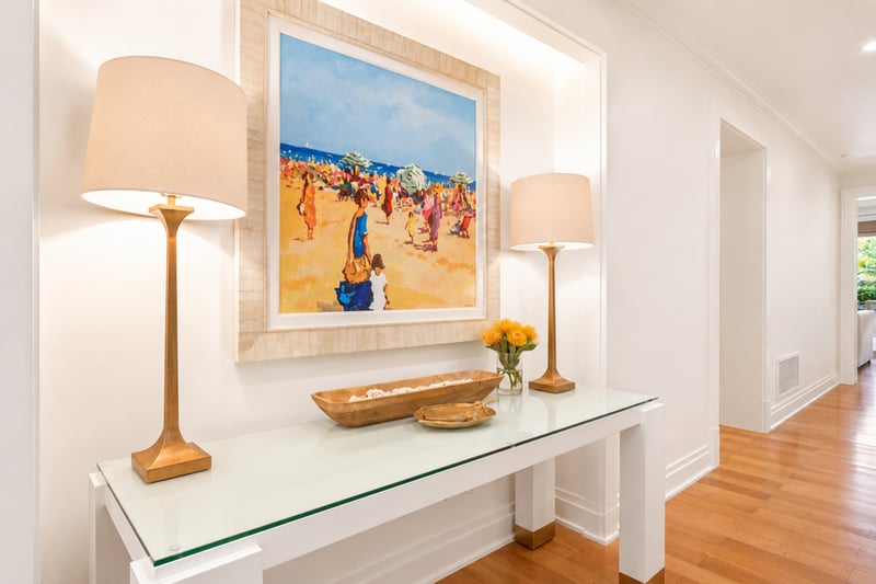 Entry hallway at The Resort at Kapalua Bay MON-2206 — brass lamps and a large framed beach-scene painting welcome guests home MON-2206