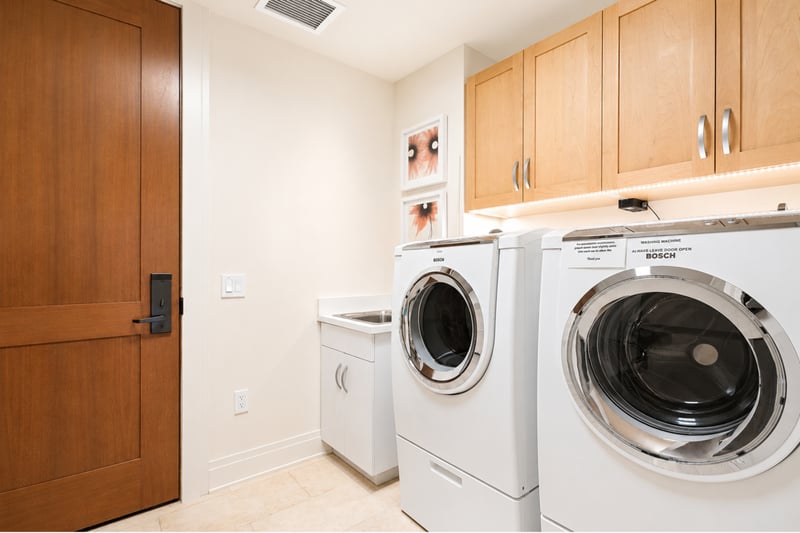 In-unit laundry at The Resort at Kapalua Bay MON-2206 — full-size Bosch washer and dryer with a utility sink MON-2206