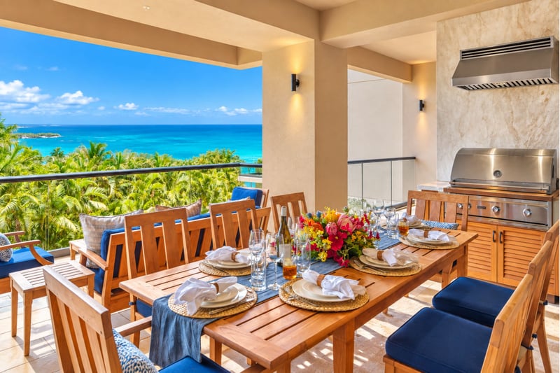 Covered lanai dining table beside a built in grill with sweeping ocean views