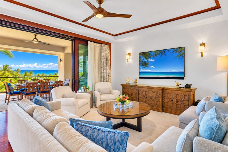 Living room with oversized sectional, television, and open sliding doors to the ocean view lanai