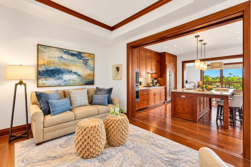 Cozy sitting room with sofa, woven poufs, and coastal artwork beside the kitchen