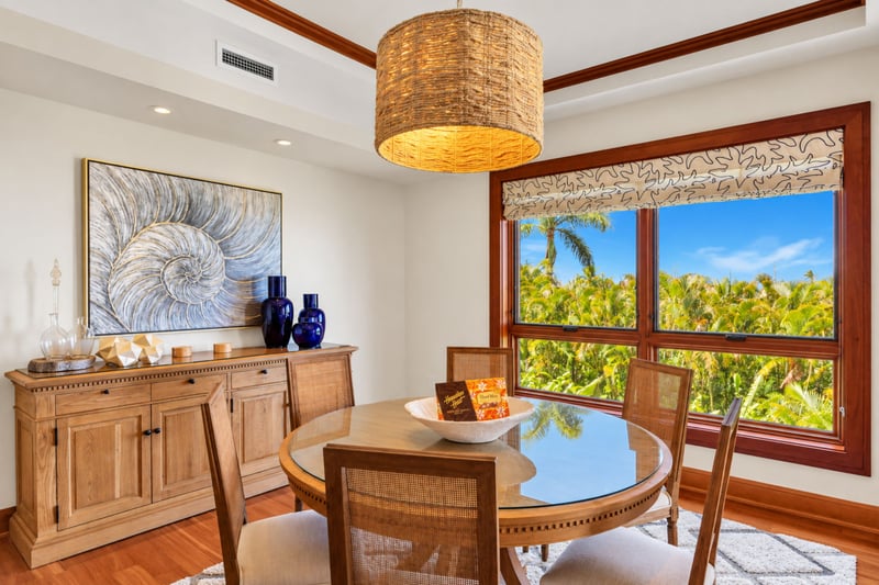 Round dining table for six with a woven pendant light and tropical garden views