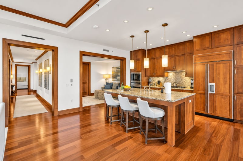 Kitchen with granite island, bar seating for three, and built in refrigerator under warm pendant lighting