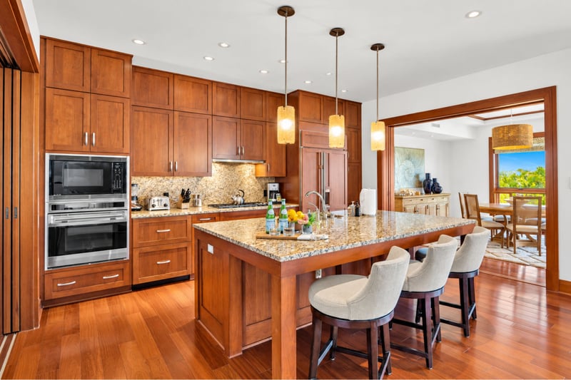 Chef's kitchen with stone backsplash, wall oven and microwave, gas cooktop, and island seating