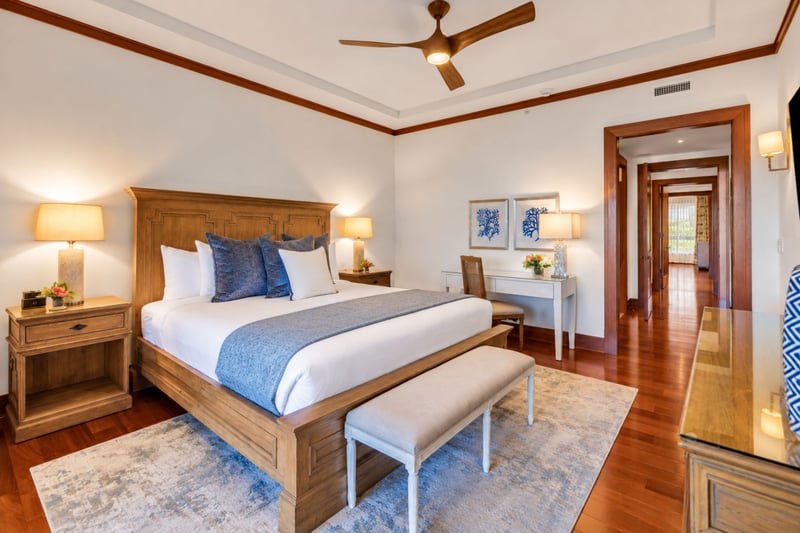 Primary bedroom with carved wood bed, writing desk, and ceiling fan