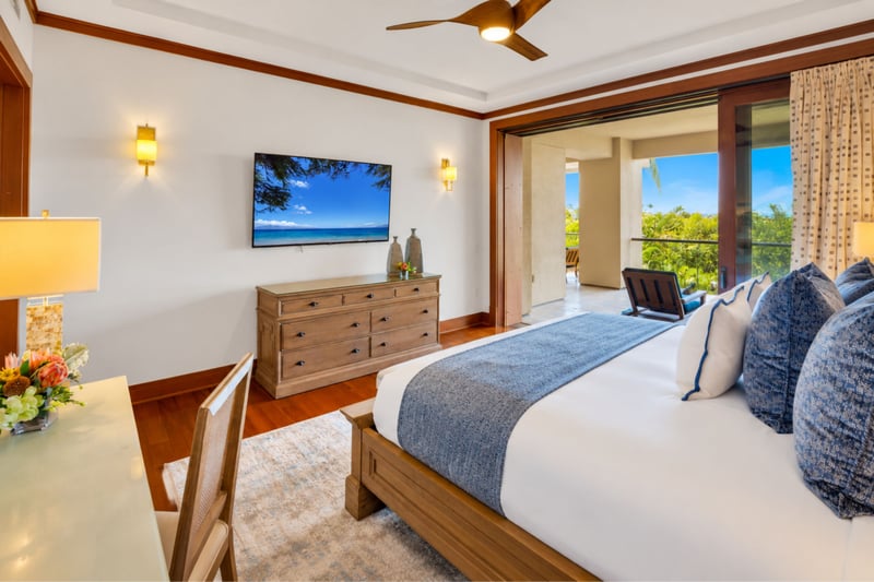Primary bedroom with wall mounted television, dresser, and sliding doors to the lanai