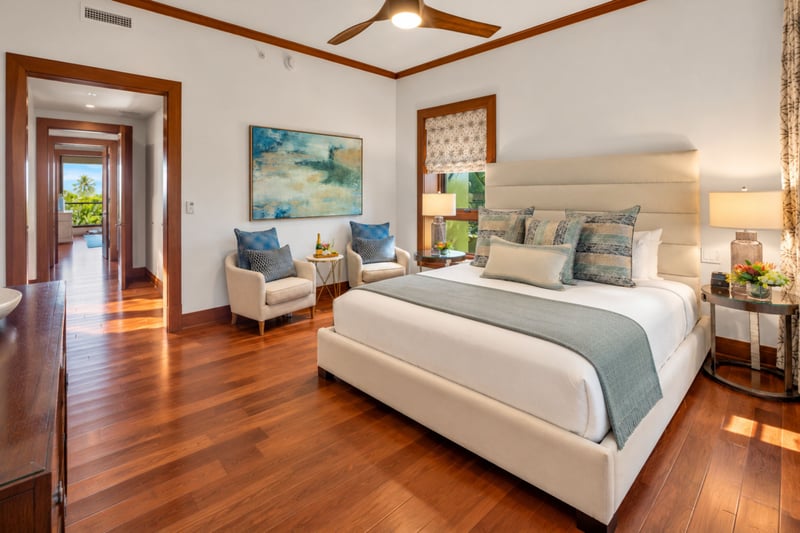 Second bedroom with ceiling fan, coastal artwork, and a hallway leading to the lanai