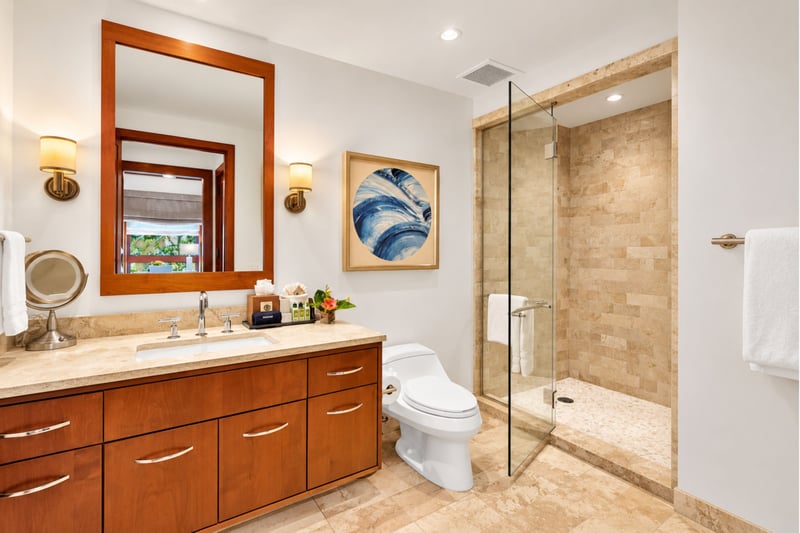 Guest bathroom with single sink vanity, glass enclosed shower, and framed coastal art