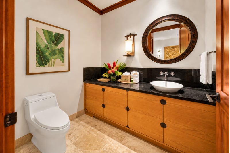 Powder room with vessel sink, dark stone counter, and tropical artwork
