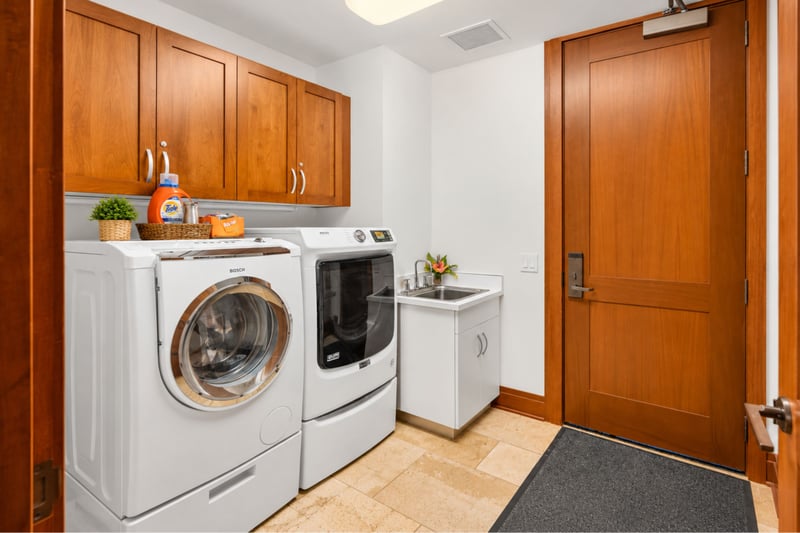 Laundry room with front load washer and dryer, utility sink, and overhead cabinets