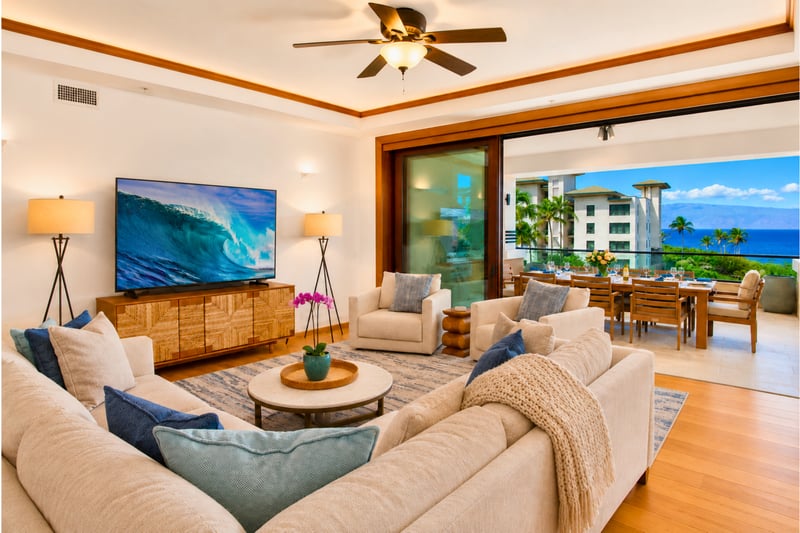 Living room at The Resort at Kapalua Bay MON-6301 — sectional seating opens directly to the dining lanai and ocean beyond