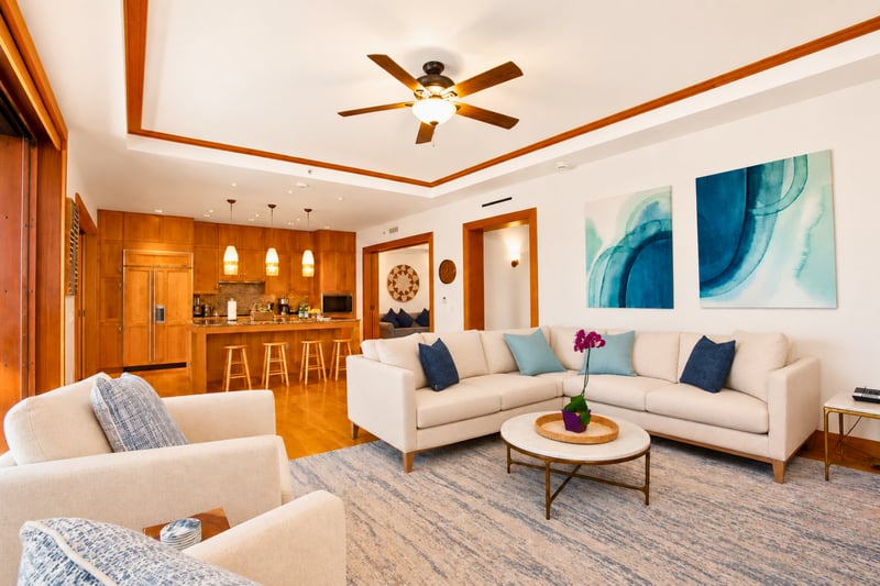 Great room at The Resort at Kapalua Bay MON-6301 — plush sectional with teal and navy accent pillows beneath watercolor wave art