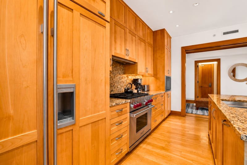 Kitchen prep space at The Resort at Kapalua Bay MON-6301 — granite counters, gas cooktop, and warm wood cabinetry