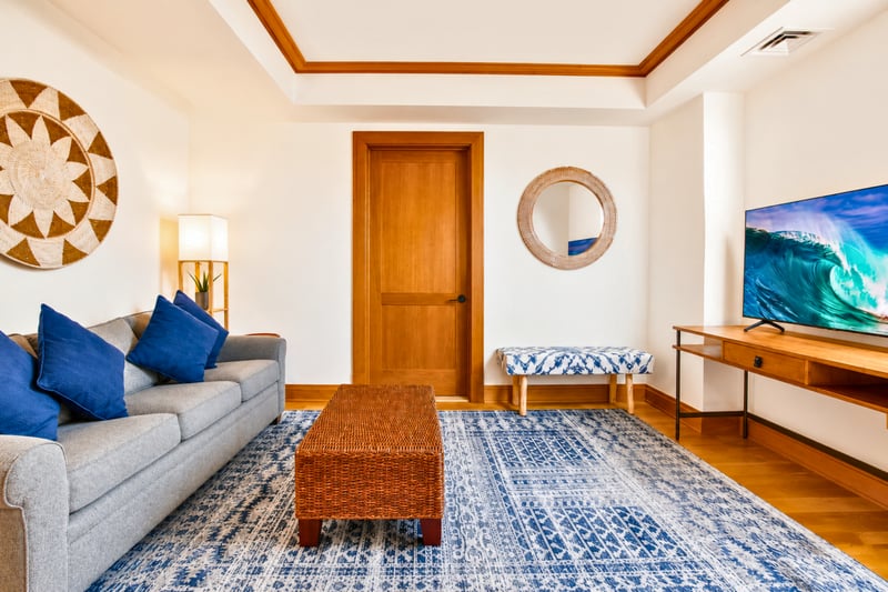 Media room at The Resort at Kapalua Bay MON-6301 — cozy sofa, woven wall art, and smart TV for a relaxed night in