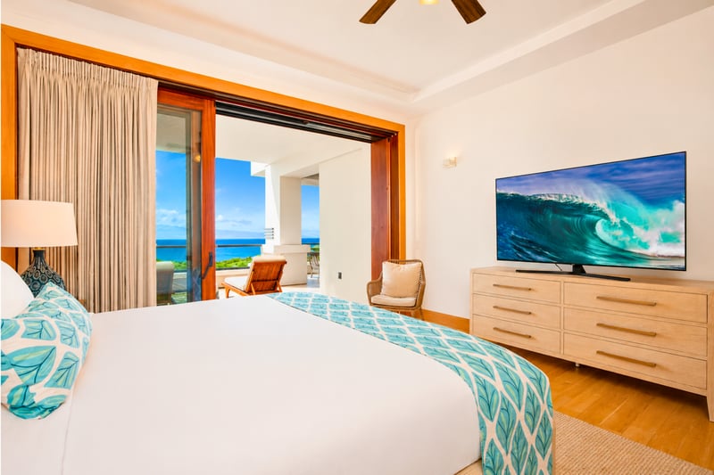Primary suite at The Resort at Kapalua Bay MON-6301 — king bed, dresser-mounted TV, and sliding doors to a private oceanview balcony