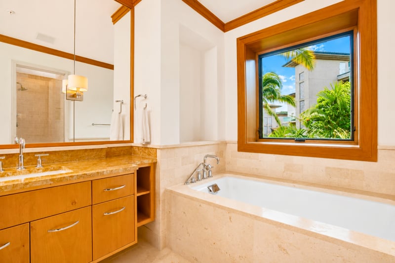 Guest bath vanity at The Resort at Kapalua Bay MON-6301 — granite double vanity with tub and glass shower beyond