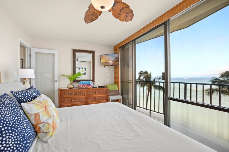 Relax in a sunlit master suite featuring a soft king bed, tropical decor, and sweeping views of the Pacific horizon