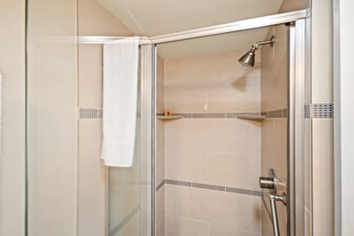 Step into a sleek glass-enclosed shower with elegant tile detailing in this beautifully appointed guest bathroom