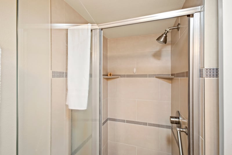 Step into a sleek glass-enclosed shower with elegant tile detailing in this beautifully appointed guest bathroom