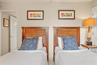 Enjoy plush twin beds adorned with bold pillows, breezy linens, and warm wood frames that echo a serene island escape