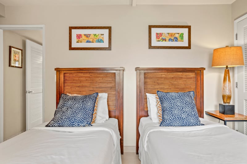 Enjoy plush twin beds adorned with bold pillows, breezy linens, and warm wood frames that echo a serene island escape