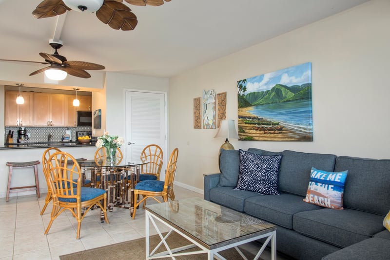 Relax in the living room where palm-leaf fans, plush seating, and coastal charm create the ultimate beachy vibe