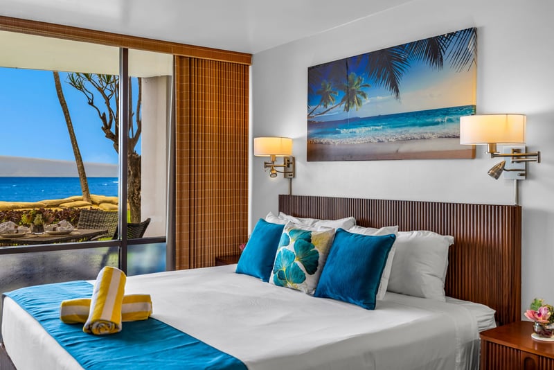 This suite features a king bed with crisp white linens and a sliding door opening to ocean views