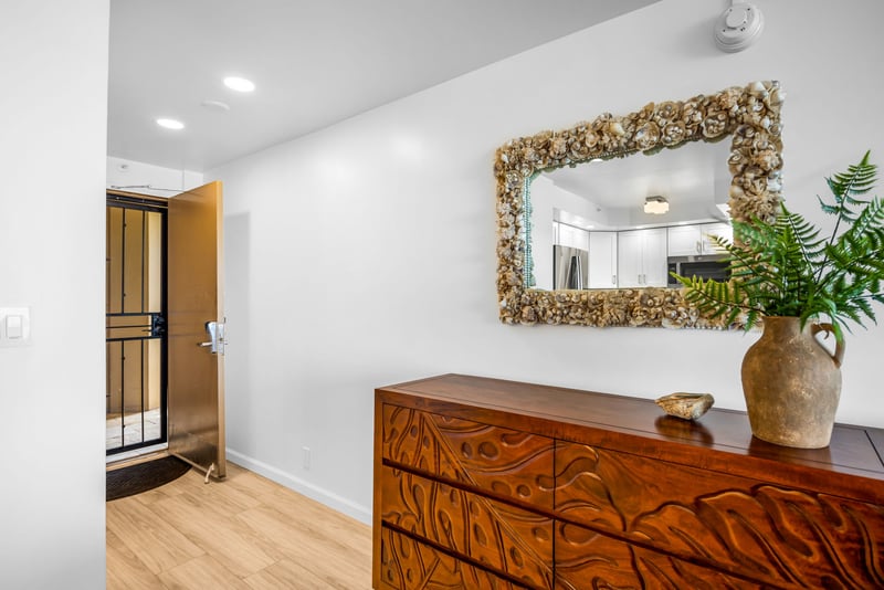 The entry sets a welcoming tone with warm wood tones, a mirror, and natural light from the interior