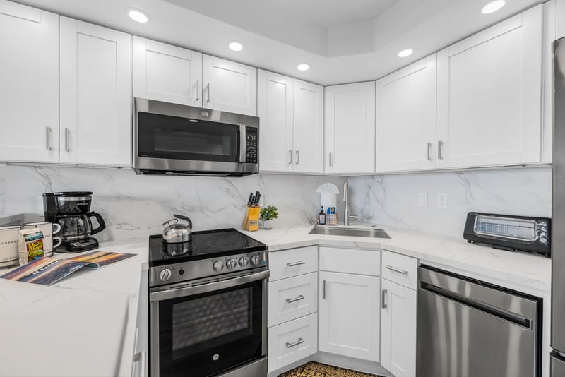 White cabinetry and quartz-style counters keep the kitchen bright and functional from every angle