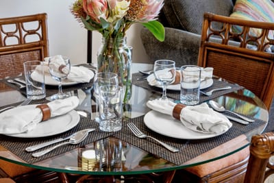Gather at this tropical-inspired dining table with carved wood chairs, soft lighting, and vibrant floral accents