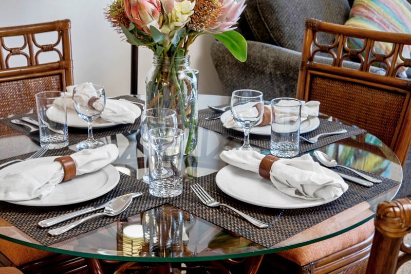 Gather at this tropical-inspired dining table with carved wood chairs, soft lighting, and vibrant floral accents WH1-1211