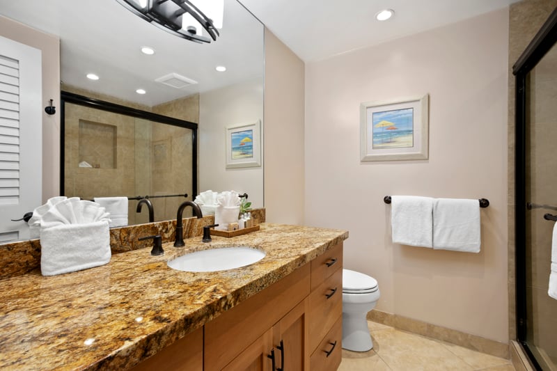 Granite counters, warm wood tones, and a spa shower pair with ocean-view reflections steps away WH1-1211
