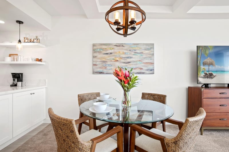 A chic blend of rattan texture, oceanic hues, and sculptural lighting create a breezy, coastal dining experience