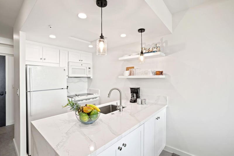Bright, modern kitchen with sleek finishes, island seating, and tropical touches, perfect for relaxed vacation meals.