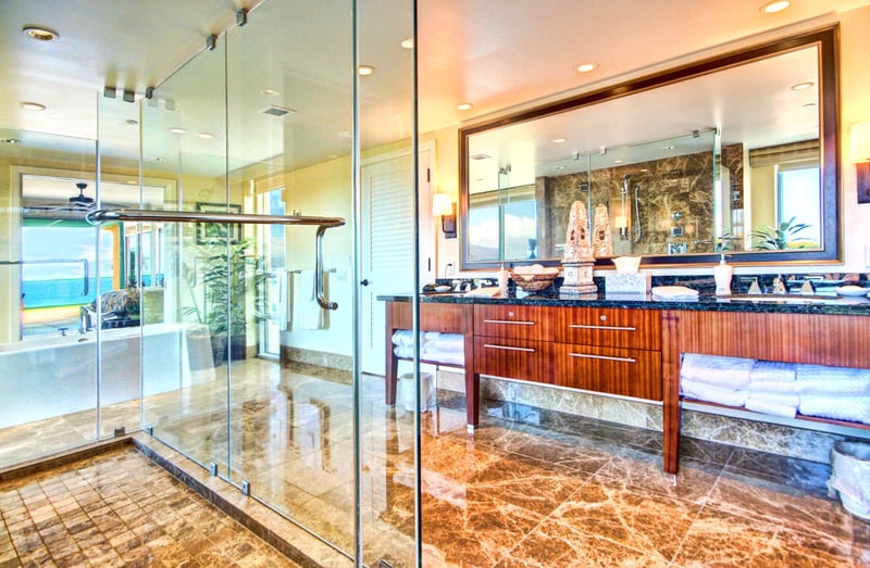 Double-vanity spa bath with full glass enclosure, soaking tub, and panoramic views of Maui’s sparkling coast