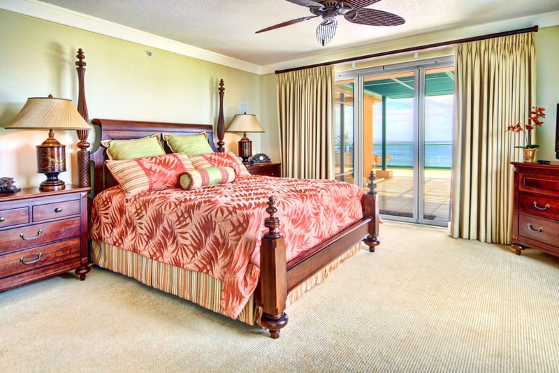 Oceanview bedroom with king bed, tropical bedding, and direct lanai access for sunrise views over the Pacific