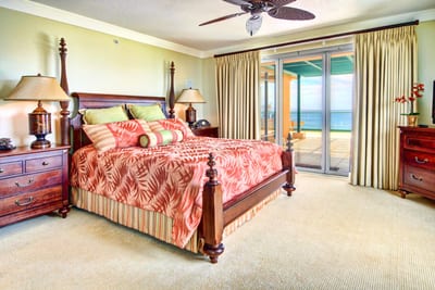 Oceanview bedroom with king bed, tropical bedding, and direct lanai access for sunrise views over the Pacific