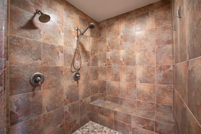 Our oversized walk-in shower features custom tilework, dual showerheads, and a bench for steamy, serene unwinding GCH-120
