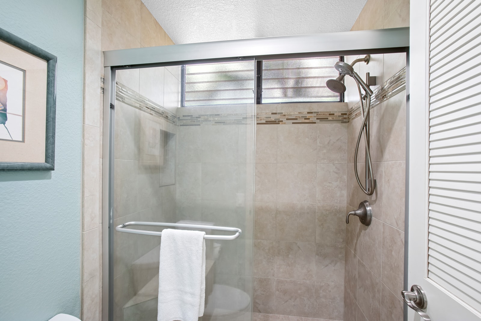 Walk-in shower with modern tile and natural light in the additional bathroom