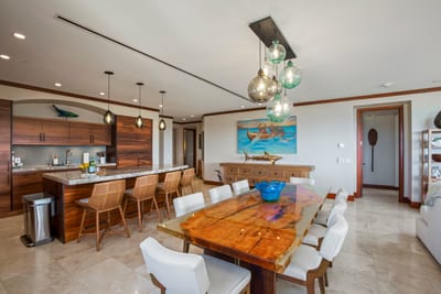 Rustic wood and modern polish collide at the dining table, where surfboard art nods approvingly from the wall