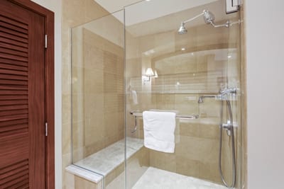 The walk-in shower’s tile glows like sun-warmed sand, and the built-in bench says, “Yes, sit and stay awhile.”
