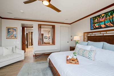 The carved headboard guards your dreams while ocean-toned pillows whisper lullabies from tropical realms