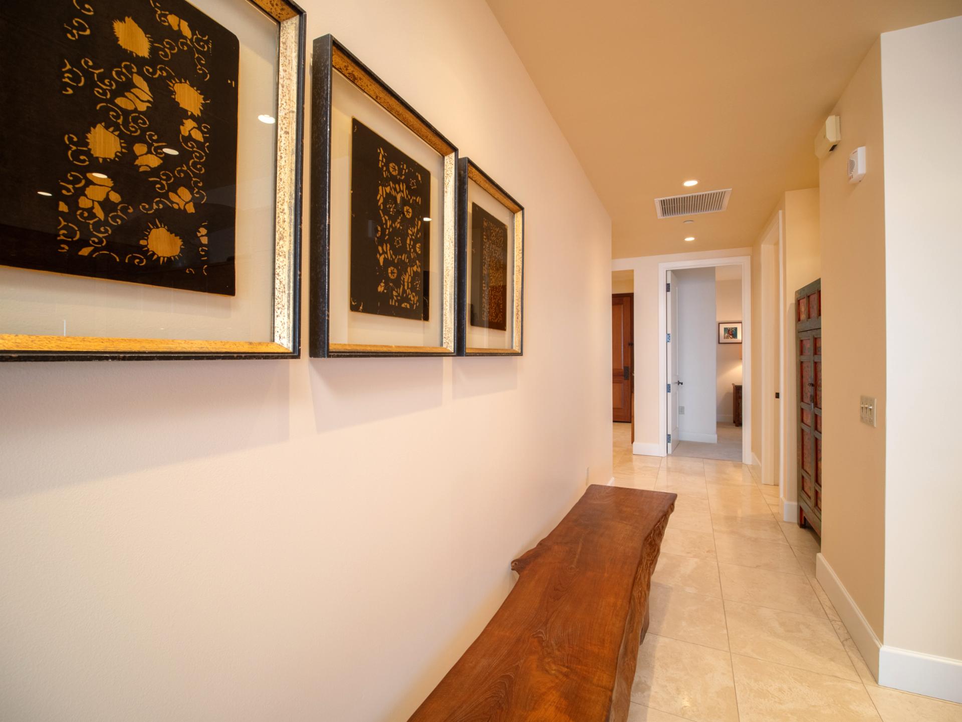 Art-lined hallway leads from bedrooms to main living, blending modern design with natural textures.