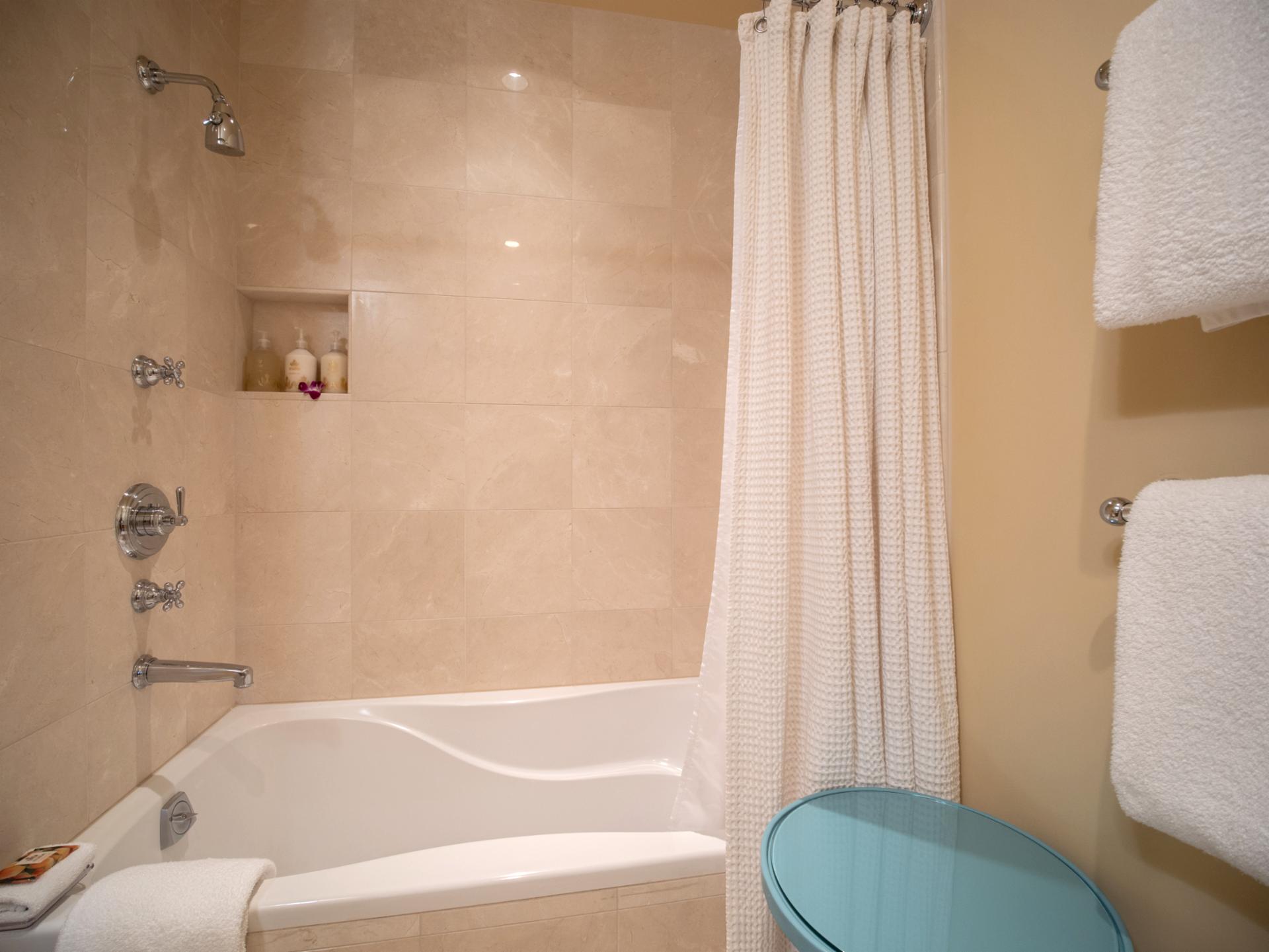 Stone tile and soft lighting create a warm, welcoming atmosphere in the hallway bath.
