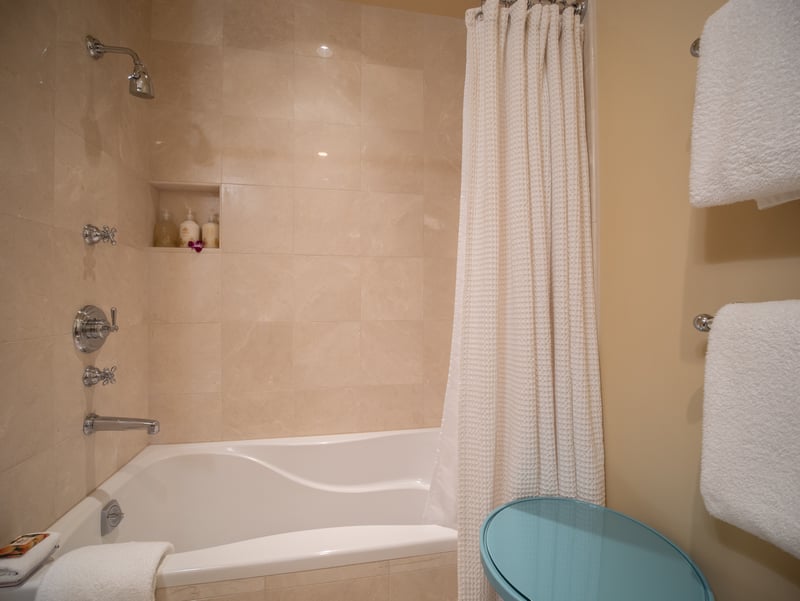 Stone tile and soft lighting create a warm, welcoming atmosphere in the hallway bath.