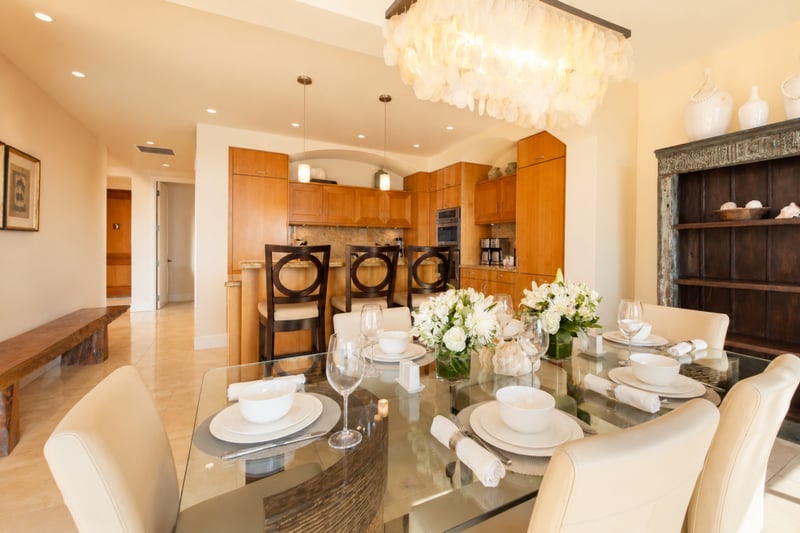 Dining and entry at Wailea Beach Villas PH505 — glass table for eight beside an antique carved cabinet and open sightline to the hallway WBV-PH505