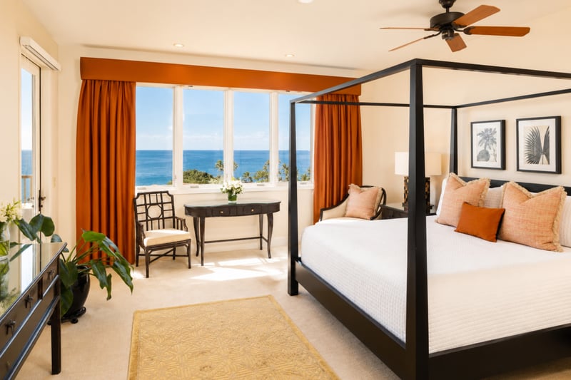 Primary bedroom at Wailea Beach Villas PH505 — coral and white linens beneath botanical art, with a private lanai just steps away WBV-PH505
